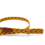 Dog leash with yellow and black pattern and brown leather patch on a white background