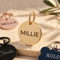 Gold personalised dog tag engraved MILLIE, with rose gold, black and blue tags from the range around it