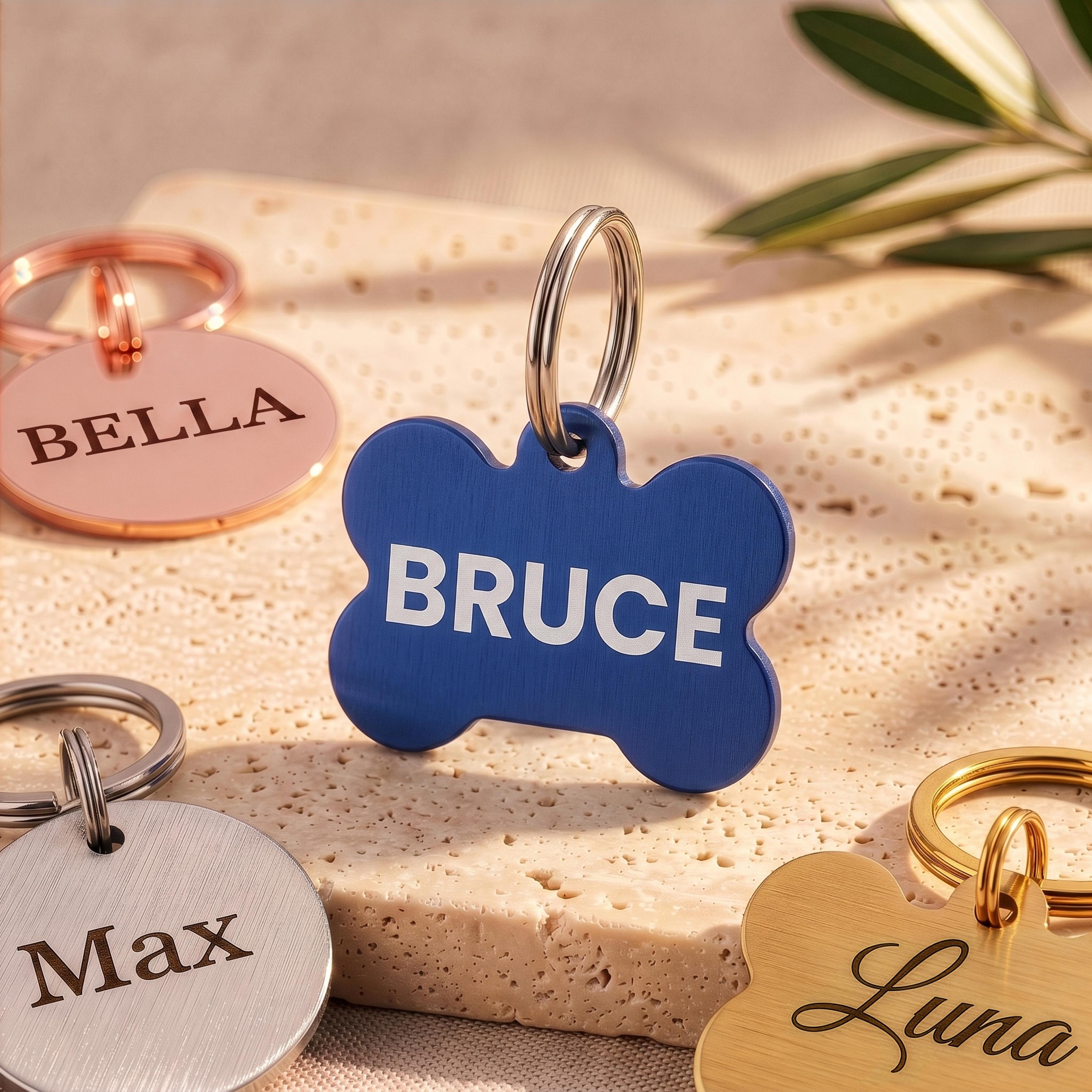 Blue bone dog tag engraved BRUCE in brushed navy, with rose gold, silver and gold tags around it