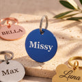 Blue round dog tag engraved Missy in brushed navy, with rose gold, silver and gold tags around it