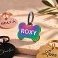 Multicolour bone dog tag engraved ROXY with a rainbow finish, with rose gold, black and gold tags around it