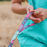 Person holding a colorful dog leash with a blurred natural background