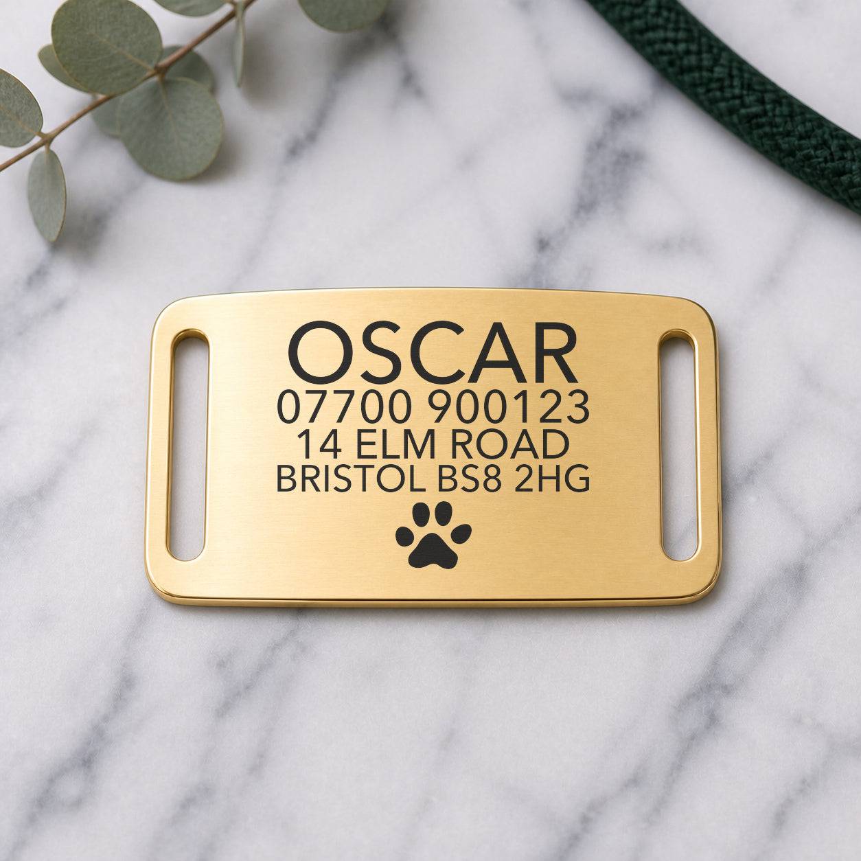 Brushed gold slide-on dog tag engraved with a name, styled on marble