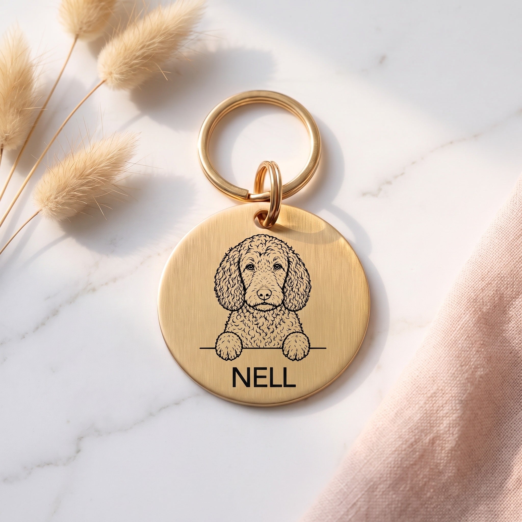 Gold Sproodle dog tag engraved with the Sproodle design and the name Nell
