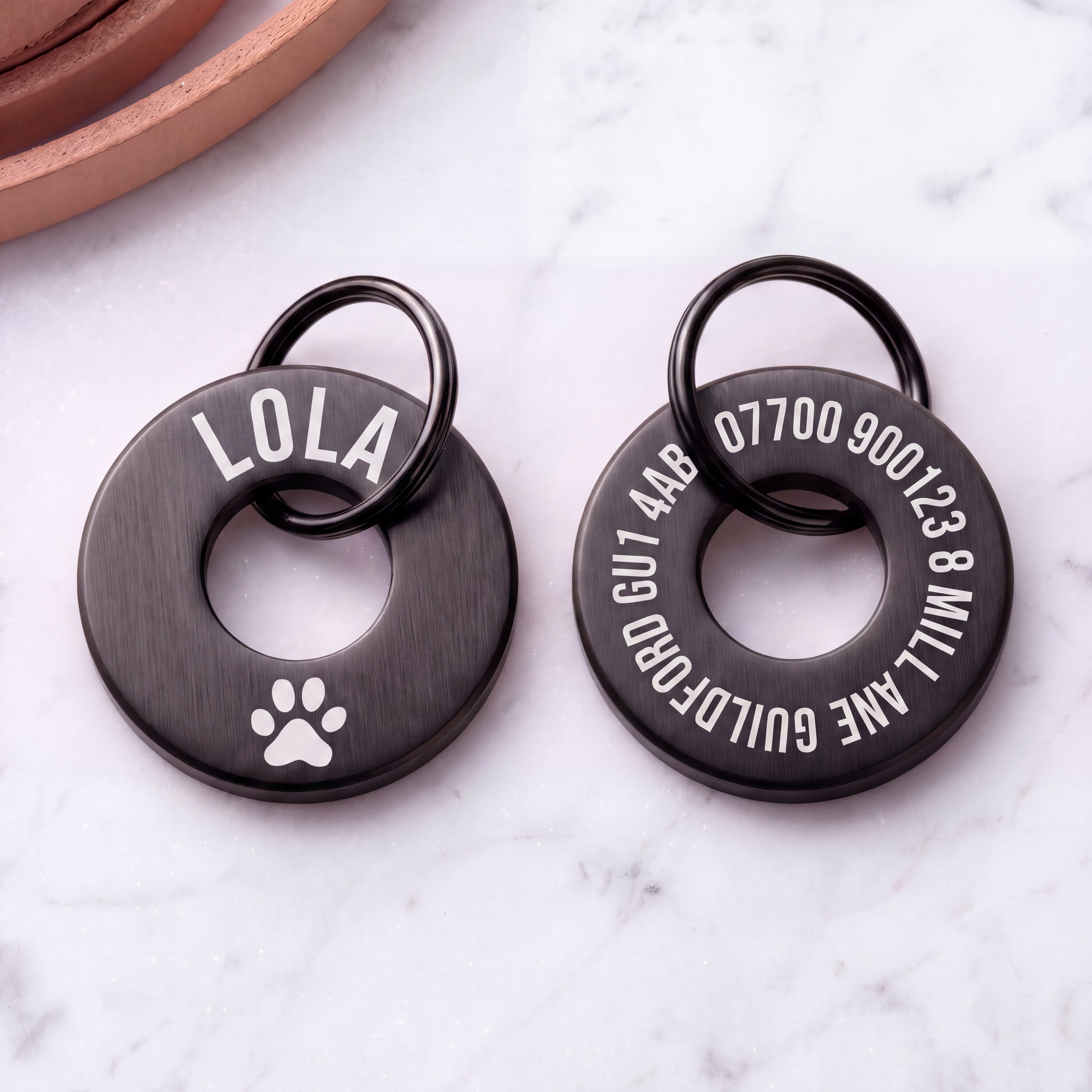 Front and back of the black washer dog tag - name and symbol on the front, contact details on the back